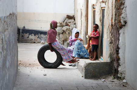 Zanzibar, Tanzania - January 1, 2016: African Muslim women holding baby her arms and her children on the street of Stone Town in Zanzibarのeditorial素材