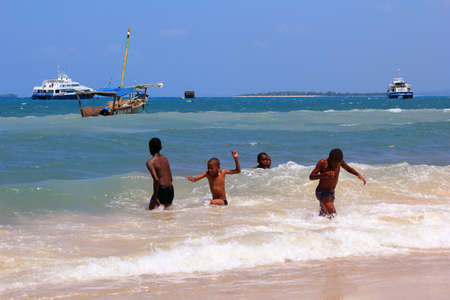 Zanzibar, Tanzania - December 30, 2015: Group of kids playing in the water on the beach of Stone Town. The capital of Zanzibar.のeditorial素材
