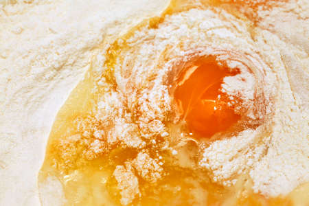 Baking ingredients. Egg on of scattered wheat flour close-up.の写真素材