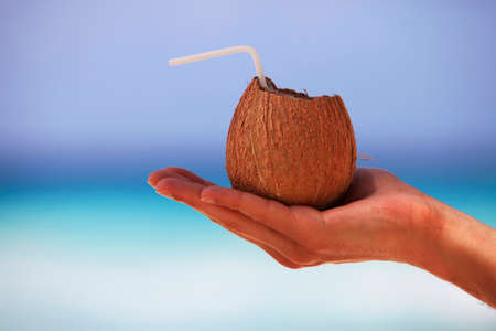 Coconut in a man's hand isolated on background of the seaの写真素材