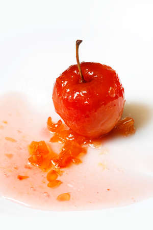Red apple in rose syrup with small pieces of zucchini over isolated white backgroundの写真素材