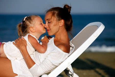 Happy mother holding her daughter on the beachの写真素材