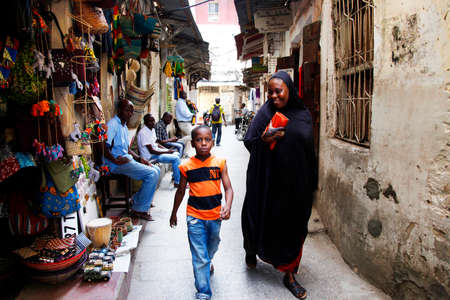 Stone town, Tanzania - December 30, 2015: Stone Town. Woman in Zanzibar all have to wear black burka when they go outside, even girls have to wear scalf on their heads. It is a Muslim life stile. Streets of the town are always lively.のeditorial素材