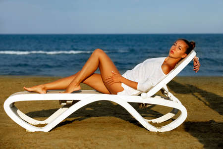 Beautiful girl on a deckchair on the coastlineの写真素材