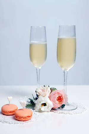 Two glasses with champagne, boutonniere with roses and cookiesの写真素材