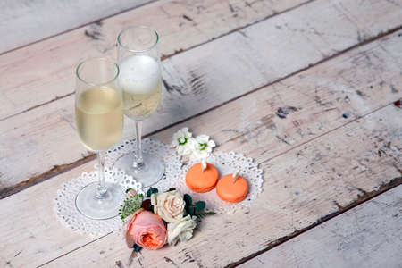 Two glasses with champagne, boutonniere with roses and cookiesの写真素材