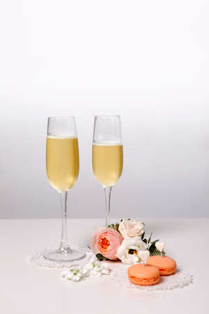 Two glasses with champagne, boutonniere with roses and cookiesの写真素材