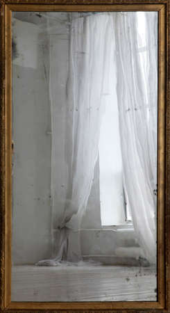 Reflection of a window with curtains in an old mirrorの写真素材
