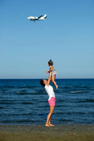 Happy mother holding her daughter on the beachの写真素材