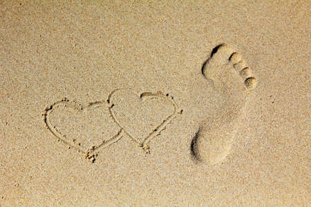 Heart and Prints of legs on sandの写真素材