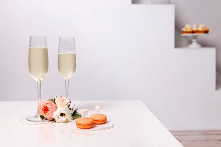 Two glasses with champagne, boutonniere with roses and cookiesの写真素材