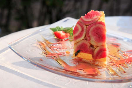 Piece of cake on a glass plate and a beeの写真素材