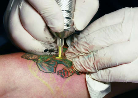 A tattoo artist applying his craft onto the hand of a femaleの写真素材
