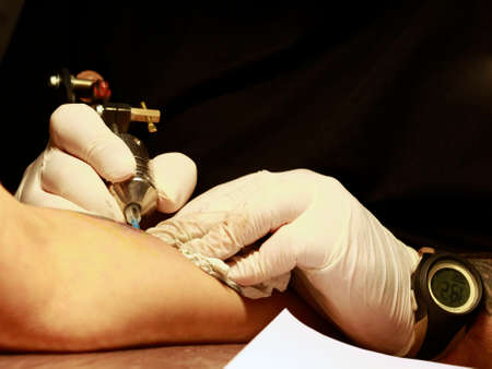 A tattoo artist applying his craft onto the hand of a female