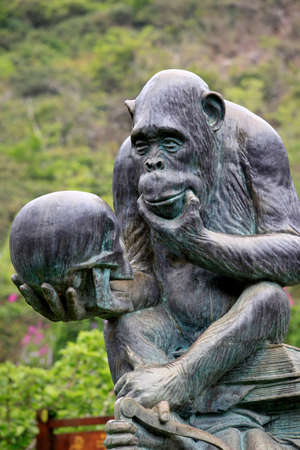 Hainan, China - 09 April, 2012  : Monkey Island Research Park - a Gorilla Statue,  by a large bronze-like statue of a monkey sitting on a pile of books with a skull in a pawon on Monkey Island 9 April 2012 , Chinaのeditorial素材
