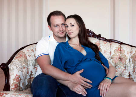 Happy beautiful pregnant woman with his husband at homeの写真素材