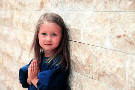 Little girl laughing in the background of stone wallの写真素材