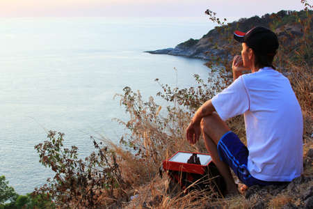 Lonely man looking with hope at horizon with sunlight during sunsetの写真素材