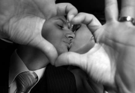 Kiss of a newly-married couple in heart from the combined handsの写真素材