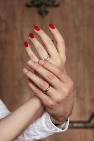 Female hands in man's hands on a wooden backgroundの写真素材