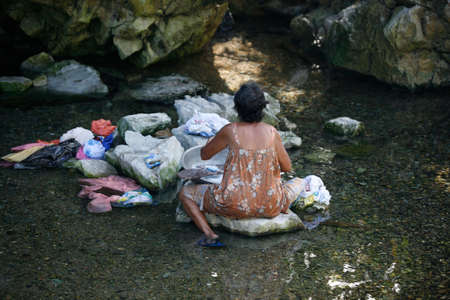 Katiklan, Philippines - October 24, 2008: Filipino elderly woman washing clothes in the river. Philippines. Island Katiklanのeditorial素材