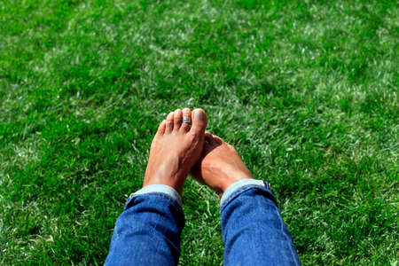 Bare feet in green grass, woman relaxing in natureの写真素材