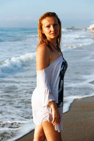 Woman in a wet dress at coast of the seaの写真素材