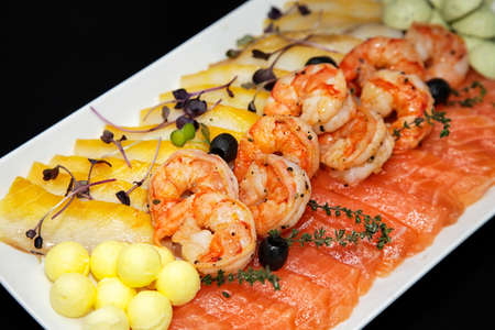 Assorted shrimp, trout and oily fish with balls of oil and black olivesの写真素材