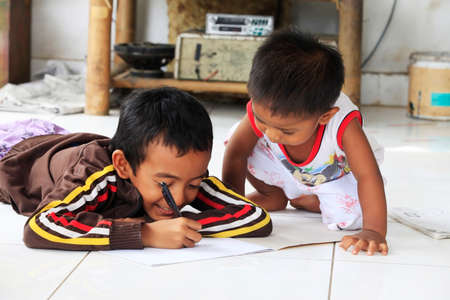Bali, Indonesia - January 24, 2009: Children of an Indonesian artist paint while sitting on the floor. Bali is famous for talented artists. Bali, Indonesiaのeditorial素材