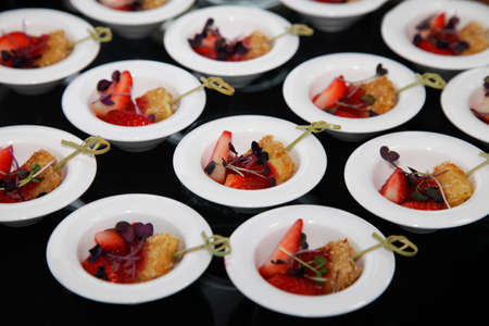 Small piece of breaded tofu with fresh strawberries in a small plate in a buffet