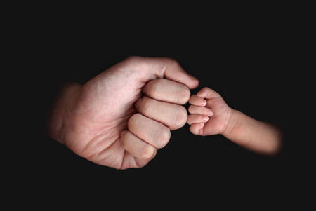Baby and adult fist bump on black background