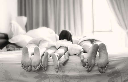 Two sisters lying on a bedの写真素材