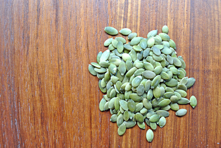 heap green pumpkin seeds on wood backgroundの写真素材