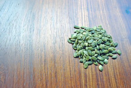 heap green pumpkin seeds on wood backgroundの写真素材