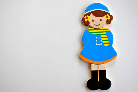 wooden figurine toy girl wearing blue wintersdress,with yellow scarf and blue hat with flowers in her hair.の写真素材