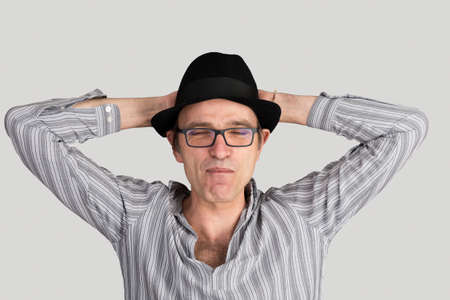 portrait of a relaxed mature caucasian with striped shirt, hat and eyeglassesの写真素材