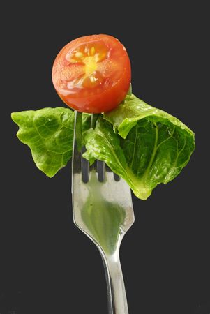 cherry-tomato and lettuce leaf impaled on forkの写真素材