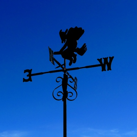 witch weather vane; silhouetted against deep blue skyの写真素材