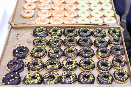 Chocolate donuts, yellow, red, orange, pink and green sugar on top, shallow focusの写真素材