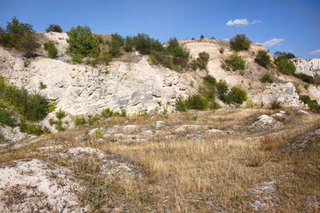 View on hills and fields from a limestone cliff at a quarry under a beautiful blue sky, abandoned white stone career, in fetesti village, Moldovaの写真素材