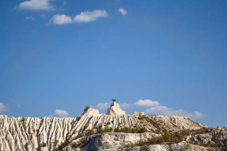 View on hills and fields from a limestone cliff at a quarry under a beautiful blue sky, abandoned white stone career, tree growing on stone, in fetesti village, Moldovaの写真素材