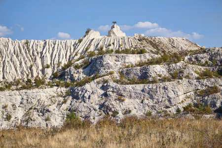 View on hills and fields from a limestone cliff at a quarry under a beautiful blue sky, abandoned white stone career, tree growing on stone, in fetesti village, Moldovaの写真素材