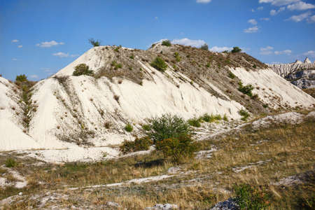 View on hills and fields from a limestone cliff at a quarry under a beautiful blue sky, abandoned white stone career, in fetesti village, Moldovaの写真素材