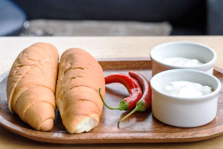 White bread, sour cream and red pepper on a wooden plateの写真素材