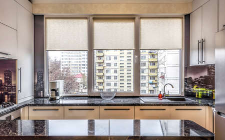Contemporary modern black colored kitchen with fitted appliances and breakfast bar, window view on buildings at chisinau albisoara street, chisinau, moldovaの写真素材