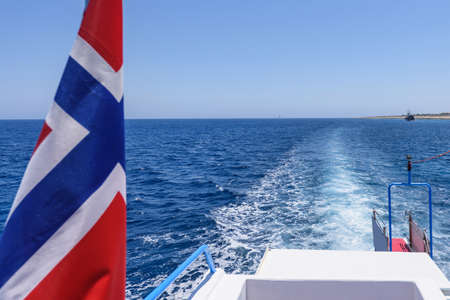 Norway flag and view from a white boat tail, white foam on immaculate water, protaras, cyprus island