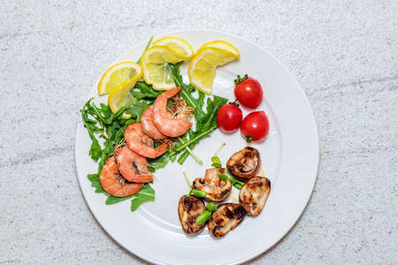 Shrimps with mushrooms and vegetables on white plate. Home cooked exotic food.
