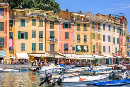 PORTOFINO, ITALY - JUNE 26, 2017: Beautiful daylight view to ships on water and buildings in Portofino city of Italy. Tourists walking on sidewalk.のeditorial素材