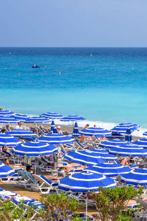 NICE COTE D'AZUR, FRANCE - JUNE 27,2017: Beautiful daylight view to beach resort. Blue water with people walking on sand and relaxing under umbrellas.のeditorial素材