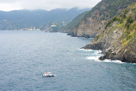 Daylight view to fishing boat and green mountains. Foggy, tusk day. Vernazza, Cinque Terre, Italy